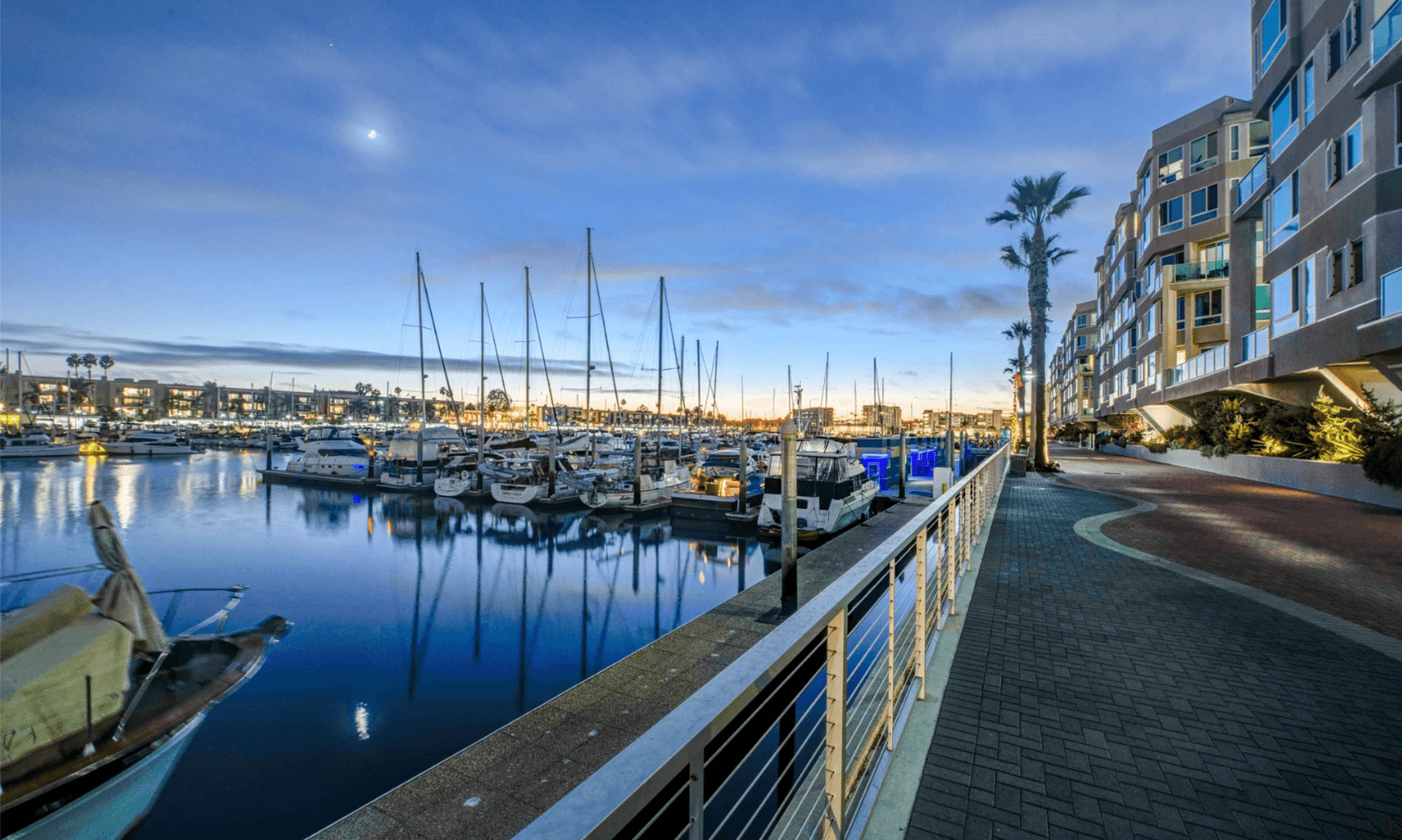 Boats moored along a marina dock at sunset
